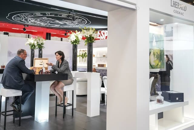 A Man and woman sitting at a high table in an office having conversation.